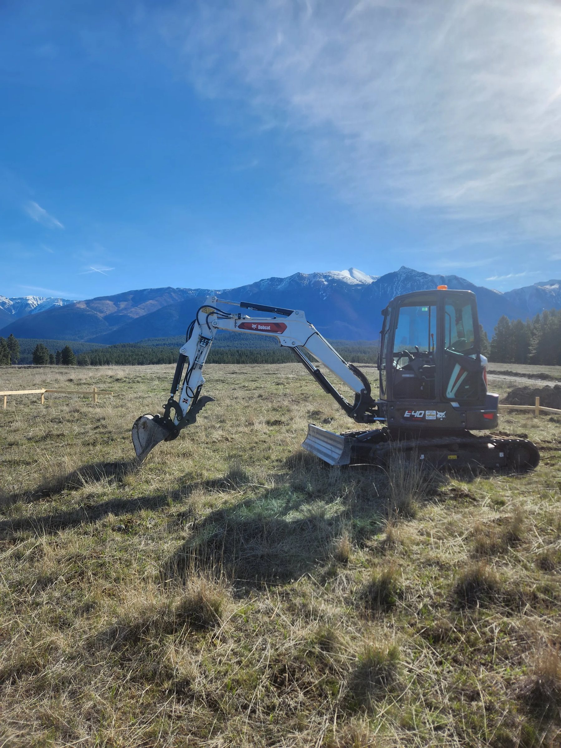 Clearflow Bobcat excavator on a site with snow-capped Rocky Mountains behind